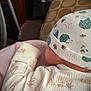 baby, infant, hat, clothing, patterned_hat, patterned_clothing, pillow, indoor, cozy, sleeping, child, soft_fabric, cute, resting, blanket, furniture, headwear, newborn, warm, comfort