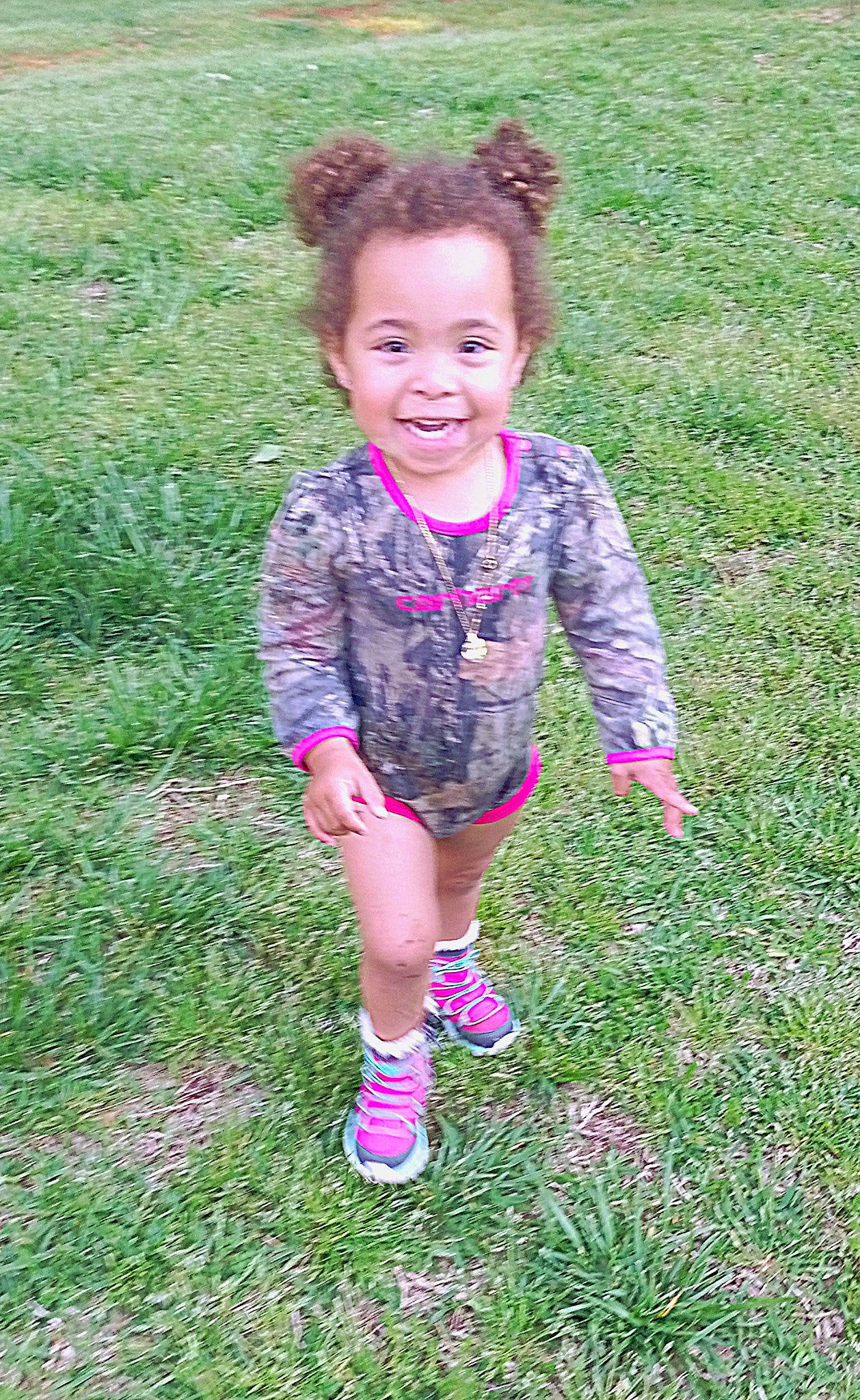 Araya is registered to the contest to win money with this photo: baby_toddler_clothing, child, face, fun, grass, grass_family, grassland, happy, joy, magenta, meadow, pattern, people_in_nature, person, pink, plant, play, recreation, sitting, sleeve