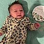 Abigail is registered to the contest to win money with this photo: baby, infant, onesie, leopard_print, hair_spike, blanket, teal, face, expression, curious, lying_down, soft_texture, decorative_sign, text, indoor, child, cute, small_hand, portrait, cozy