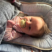 Abigail joined the competition — help win amazing prizes! baby, pacifier, blanket, infant, cushion, baby_seat, soft_texture, clothing, pink, striped, face, hand, light, shadow, hair, indoors, comfort, relaxation, child, person