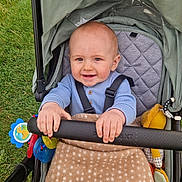 Jace joined the competition — help win amazing prizes! baby, stroller, blanket, toy, grass, child, smiling, happy, face, hand, clothing, seat, outside, infant, cute, cozy, playful, outdoor, person, bundle