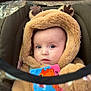 baby, infant, hood, hooded_jacket, car_seat, plush_fabric, blanket, soft_toy, toy_book, colorful, face, eyes, cheeks, portrait, closeup, cozy, warm_clothing, seat_harness, stroller_canopy, expression_curious