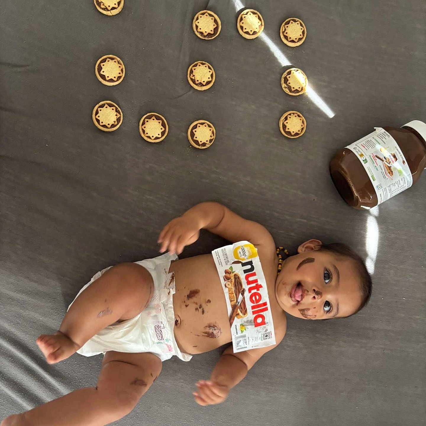 Sima a rejoint le concours — aidez-le/la à gagner de superbes lots ! baby, bed, child, chocolate, cookies, cute, diaper, face_paint, food, fun, happy, indoor, jar, lying_down, messy, nutella, playful, smiling, snack, tongue_out