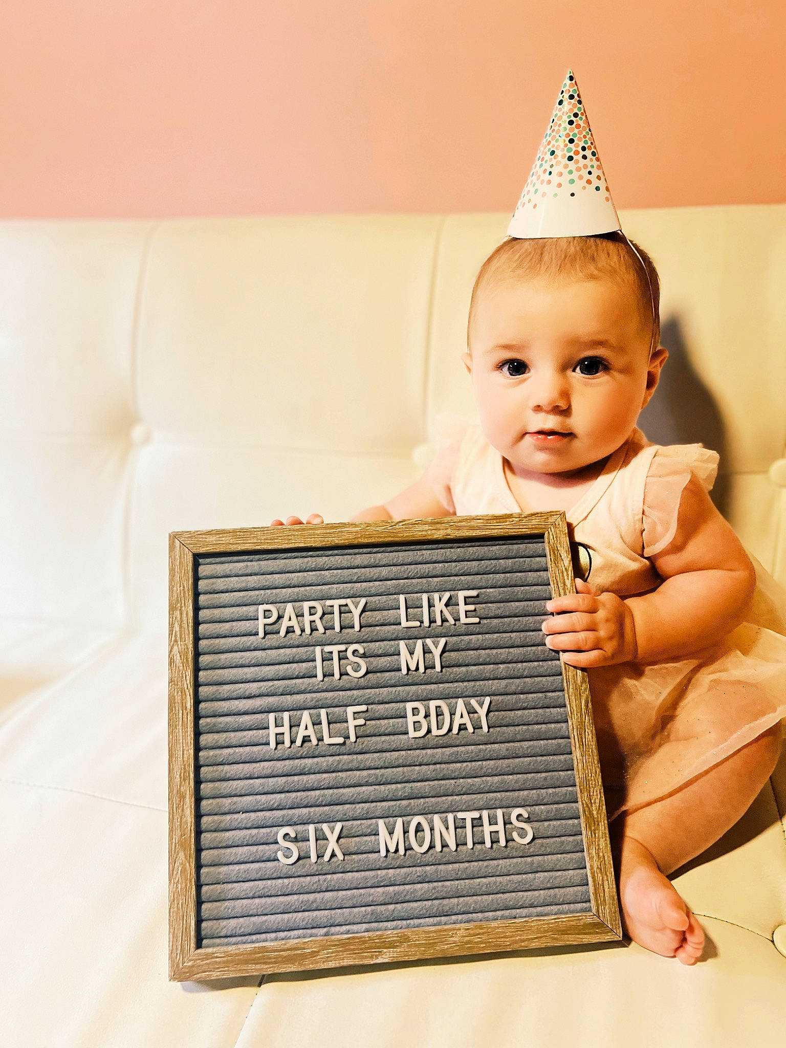 Demi is registered to the contest to win money with this photo: baby, baby_toddler_clothing, child, cone, costume_hat, fashion_accessory, font, happy, home_accessories, interior_design, ornament, party_hat, party_supply, person, photo_caption, portrait_photography, rectangle, room, sitting, toddler