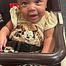 baby, bow, child, clothing, cute, eyes, face, hand, happy, headband, high_chair, indoor, infant, minnie_mouse, patterned_pants, person, seat, smile, straps, young_child