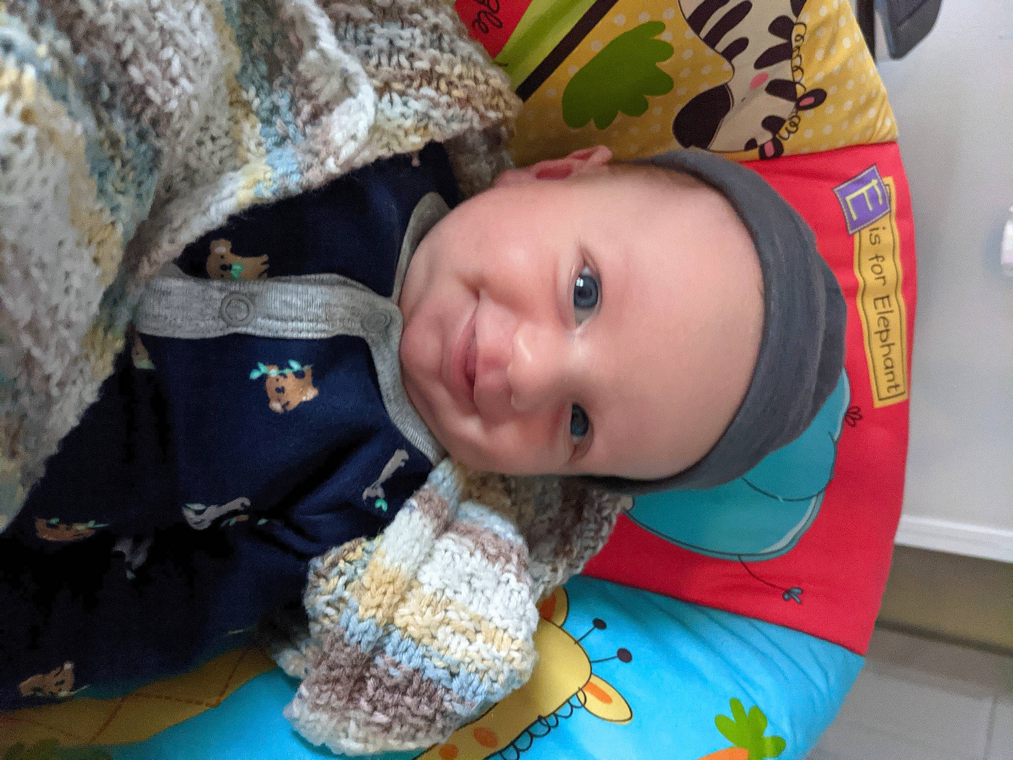 Jameson is registered to the contest to win money with this photo: baby, baby_toddler_clothing, cheek, child, fun, happy, headwear, joy, nose, pattern, person, sitting, skin, smile, textile, toddler, wood