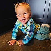 Marin a rejoint le concours — aidez-le/la à gagner de superbes lots ! child, toddler, smiling, crawling, indoor, floor, biscuit, blond_hair, plaid_shirt, pants, shoes, cabinet, happy, person, cute, young_child, casual_clothing, baby, playful, portrait