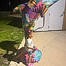 child, girl, dolphin_statue, colorful, night, outdoor, grass, concrete, sidewalk, pink_shoes, hair_bows, shorts, tshirt, toy, statue, art, shadow, lighting, playful, curious