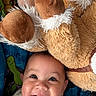 baby, smiling, face, teddy_bear, plush, toy, child, happy, cute, infant, soft, cuddly, blue_blanket, closeup, portrait, indoors, young_child, joyful, playful, adorable