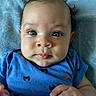 Ezrah is registered to the contest to win money with this photo: baby, blanket, blue_eyes, blue_shirt, child, chubby_cheeks, closeup, crab_prints, cute, expression, focus, hand, indoors, infant, lying_down, person, portrait, skin, soft_texture, young