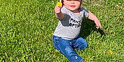 Skylar is registered to the contest to win money with this photo: casual_clothing, child, cute, dandelion, flower, grass, greenery, happy, hat, jeans, nature, outdoor, person, pink_hat, shirt, shoe, sitting, smiling, sunlight, toddler
