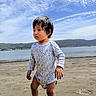 barefoot, beach, child, clouds, daytime, hands, hills, legs, nature, onesie, outdoor, person, portrait, sand, serious, shore, sky, toddler, vacation, water
