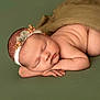 newborn, baby, sleeping, headband, flower, green_background, blanket, skin, peaceful, cute, infant, portrait, soft_light, closeup, resting, hands, face, naked, lying_down, child