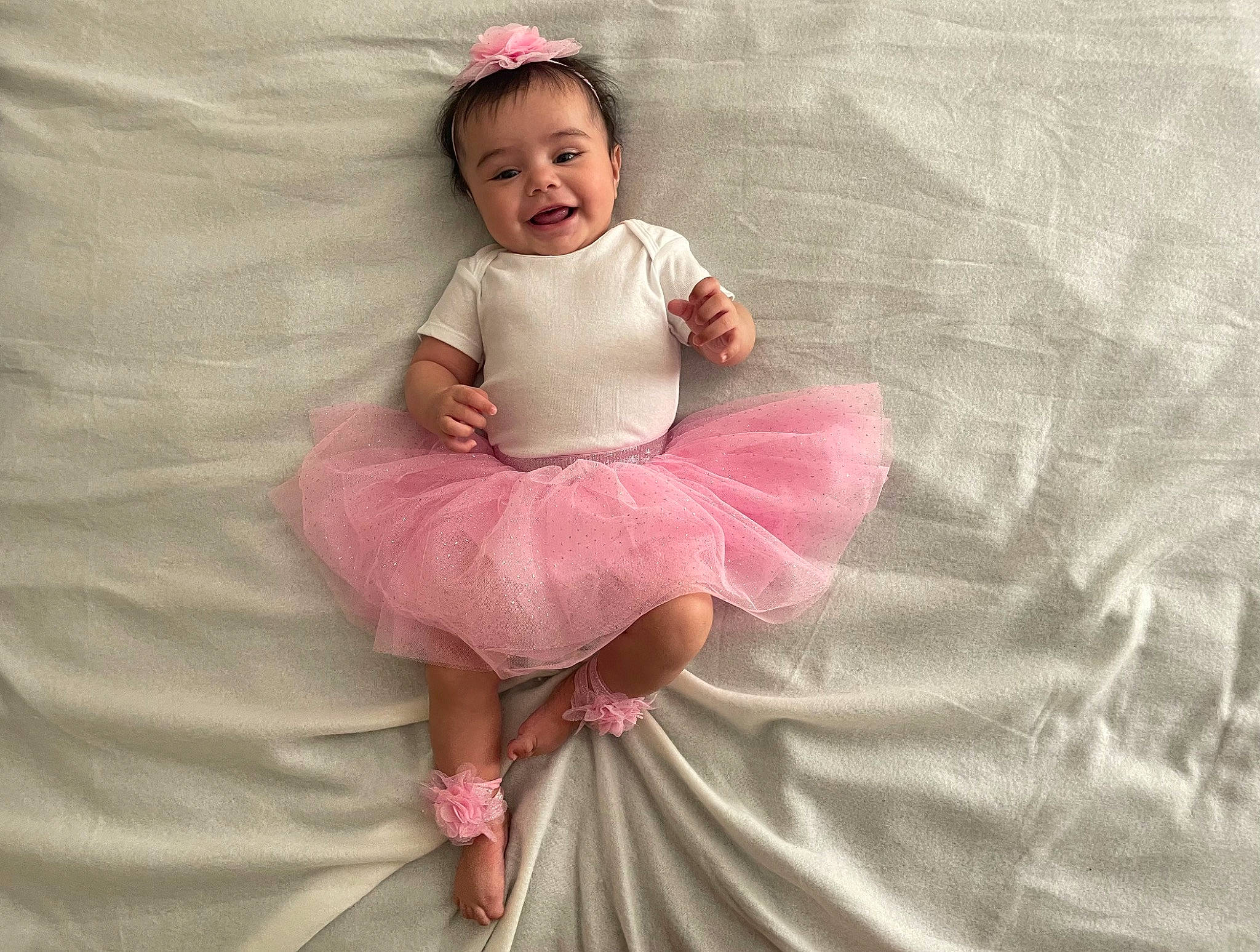 Milani is registered to the contest to win money with this photo: baby, baby_toddler_clothing, cheek, child, day_dress, dress, embellishment, face, happy, joy, linens, magenta, one_piece_garment, pattern, peach, person, pink, ruffle, sitting, sleeve