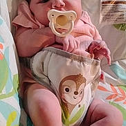 Armani is registered to the contest to win money with this photo: baby, infant, pacifier, diaper, monkey_design, pink_clothing, lying_down, portrait, face, hands, feet, blanket, crib, nursery, indoor, close_up, awake, serious_expression, baby_bedding, photograph