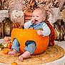 Jesse is registered to the contest to win money with this photo: baby, pumpkin, smiling, autumn, fall, decor, lantern, dried_flowers, orange, blue_clothing, cute, happy, indoor, seasonal, child, carved_pumpkin, woven_mat, footwear_free, portrait, festive