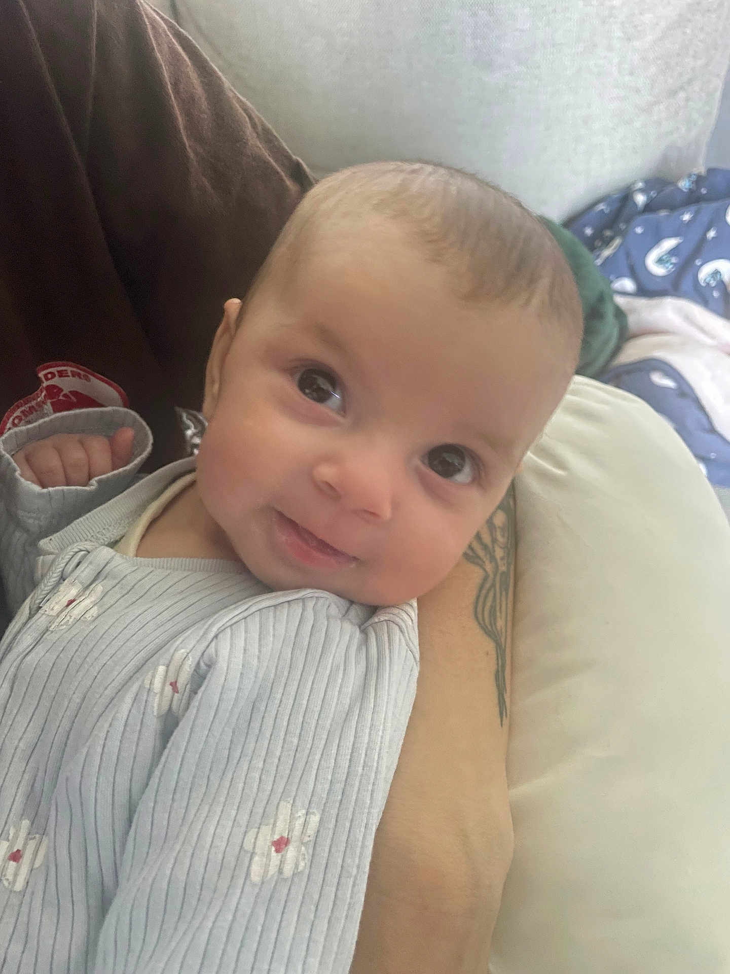 Iuna participe au concours pour gagner de l'argent avec cette photo : baby, infant, smile, face, eyes, onesie, sleeve, hand, arm, tattoo, pillow, blanket, bedding, sofa, close_up, portrait, indoor, caregiver, gaze_up, cute