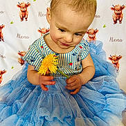 Alena joined the competition — help win amazing prizes! toddler, child, flower, blue_tutu, striped_shirt, yellow_flower, curious, sitting, background_pattern, orange_calf, name_text, cute, indoor, portrait, smiling, baby, clothing, fabric, person, playful