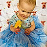 toddler, child, flower, blue_tutu, striped_shirt, yellow_flower, curious, sitting, background_pattern, orange_calf, name_text, cute, indoor, portrait, smiling, baby, clothing, fabric, person, playful