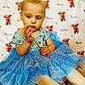 Alena joined the competition — help win amazing prizes! toddler, child, flower, blue_tutu, striped_shirt, blanket, pattern, cartoon_cow, name_text, sitting, curious, yellow_flower, indoor, cute, baby, playful, soft_texture, clothing, portrait, hands