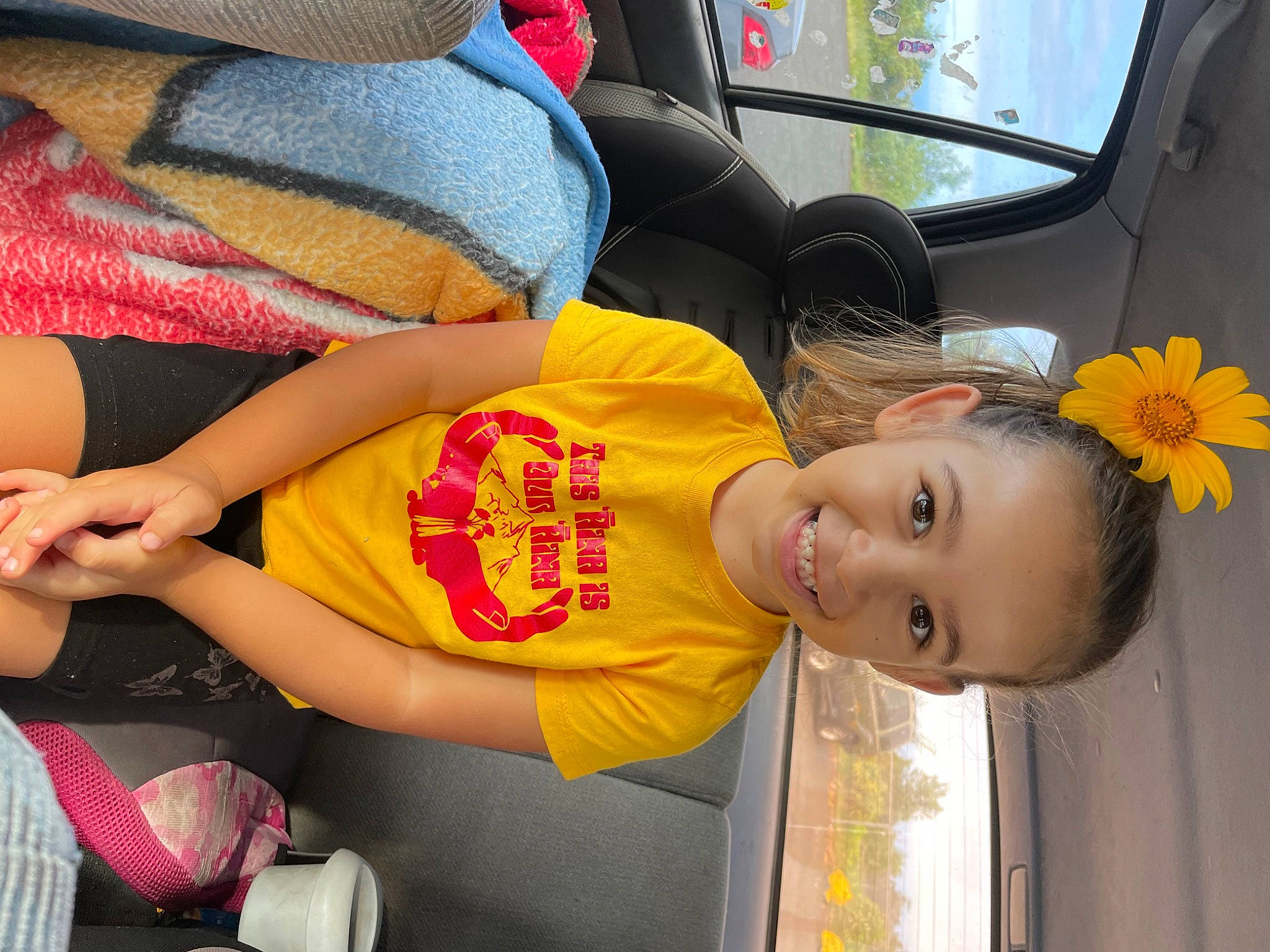 Kaya is registered to the contest to win money with this photo: auto_part, bag, car_seat, child, comfort, elbow, facial_expression, family_car, finger, flower, fun, happy, human_leg, joy, person, smile, thigh, toddler, travel, vehicle_door