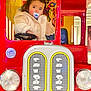 toddler, child, pacifier, toy_bus, red, beige_jacket, indoor, steering_wheel, play_area, colorful, face, portrait, cute, window, cartoon, seat, person, playground, clothing, young_child