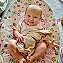 Isla is registered to the contest to win money with this photo: baby, baby_rocker, blanket, carpet, child, clothing, comfort, cute, footwear, happy, home, indoors, infant, patterned_fabric, person, playful, relaxing, seated, smiling, toy