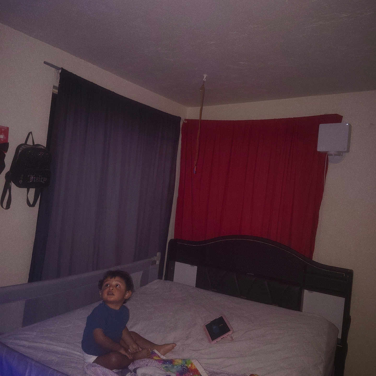 Obed is registered to the contest to win money with this photo: bed, bedroom, blanket, blue_shirt, child, colorful_blanket, curtains, flash_photography, furniture, home, indoor, looking_up, nighttime, portrait, purple, red, short_hair, sitting, tablet, toddler