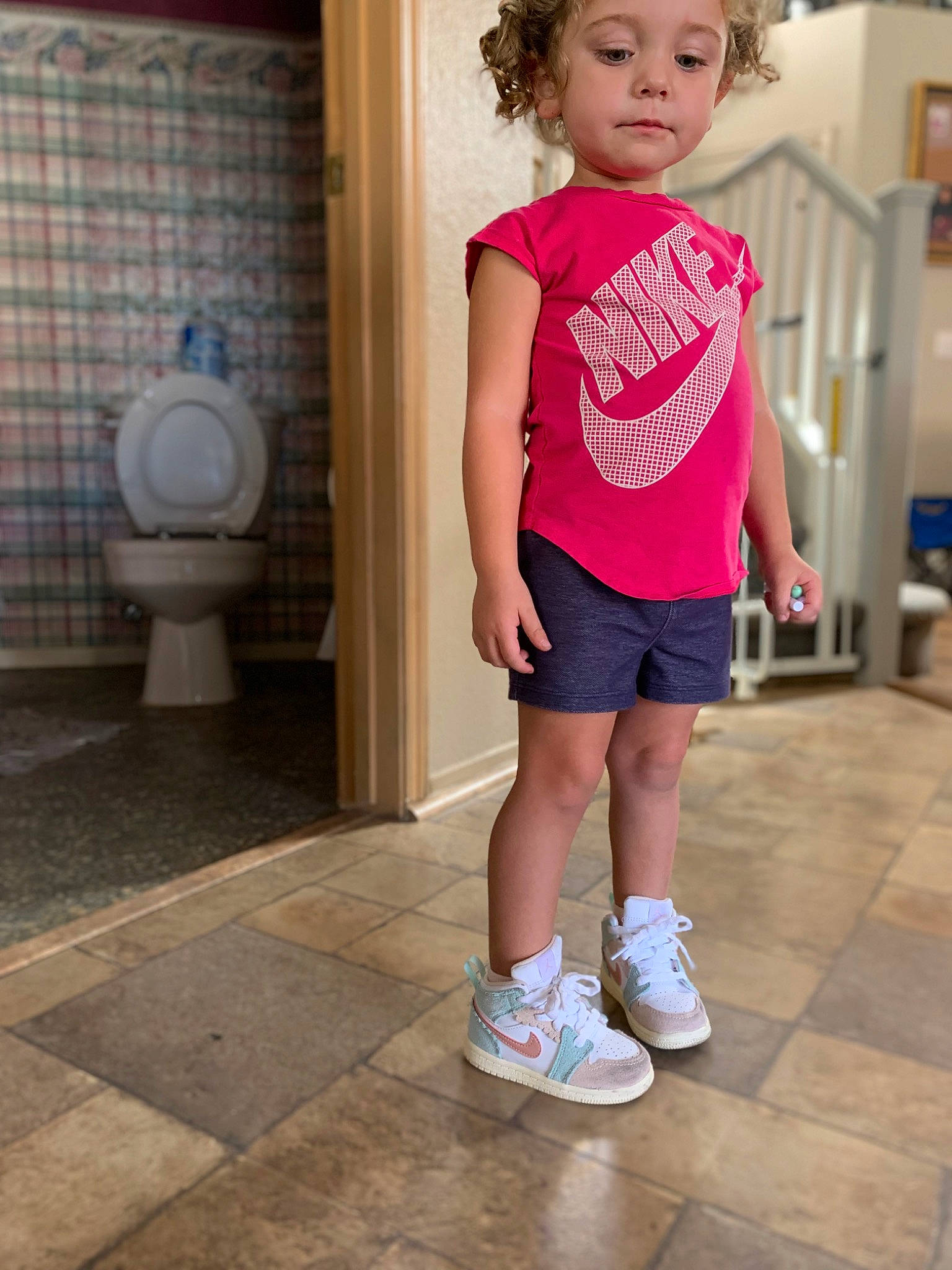Jessie is registered to the contest to win money with this photo: bathroom, blue, clothing, electric_blue, flooring, footwear, happy, human_leg, knee, person, photograph, pink, plumbing_fixture, shorts, sleeve, snapshot, sportswear, t_shirt, thigh, toddler