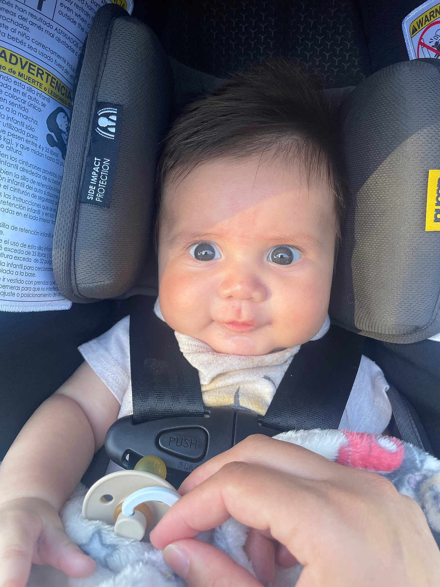 Liam is registered to the contest to win money with this photo: baby, infant, car_seat, child, pacifier, blanket, hand, straps, face, eyes, clothing, safety, seat_belt, cute, expression, indoor, head_support, skin, person, newborn