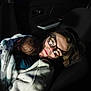 baby, infant, child, person, glasses, nose_ring, blanket, car_interior, car_seat, car_door, portrait, low_light, nighttime, cuddle, cozy, hair, head, jacket, sleeping_baby, expression