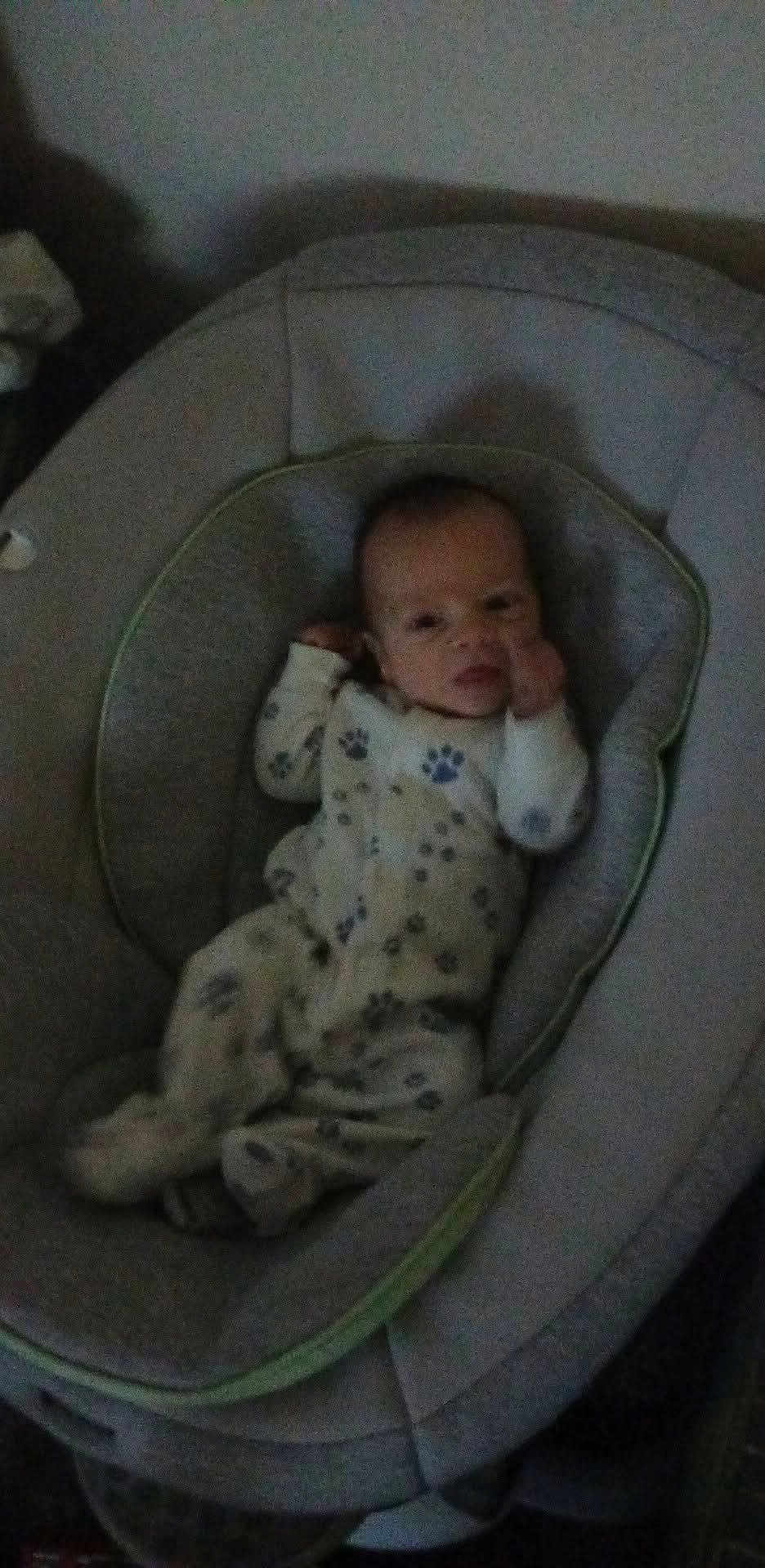 Dalton is registered to the contest to win money with this photo: baby, infant, child, onesie, pajamas, paw_prints, baby_bouncer, seat, cushion, portrait, face, head, indoors, cozy, sleepwear, lying_down, small_person, nursery_item, looking_at_camera, soft_furniture