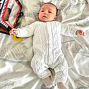 Iyad a rejoint le concours — aidez-le/la à gagner de superbes lots ! baby, infant, white_knitted_outfit, blanket, toy, mirror, reflection, soft_lighting, lying_down, curious, indoor, child, cute, patterned_blanket, socks, small_hands, face, head, comfortable, peaceful