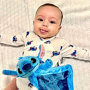 Iyad participe au concours pour gagner de l'argent avec cette photo : baby, blanket, clothing, cuddly, cute, happy, head, indoor, infant, lying_down, newborn, onesie, patterned_onesie, plush_toy, portrait, smile, soft_toy, stitch, tongue_out, wide_eyes