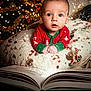 Henry joined the competition — help win amazing prizes! baby, child, christmas_tree, holiday, pajamas, book, magic, sparkles, cushion, indoors, festive, decorations, holiday_lighting, curious, portrait, face, hands, cozy, seasonal, closeup