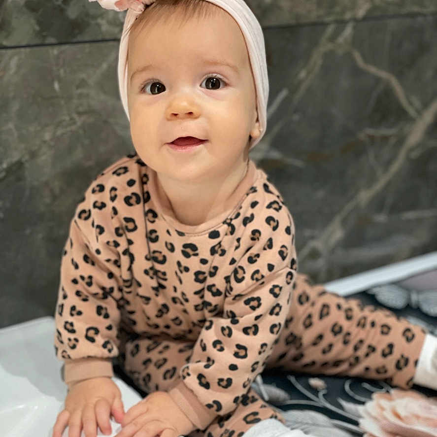 Amelia participe au concours pour gagner de l'argent avec cette photo : baby, bow, child, curious, cute, fashion, floor_mat, floral_pattern, hands, headband, indoors, infant, leopard_print, marble_wall, outfit, portrait, sitting, smile, white_shoes, young