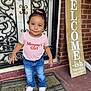 accessories, child, clothing, door, face, female, footwear, girl, head, homedecor, jeans, mat, pants, person, photography, portrait, rug, shoe, standing, t_shirt