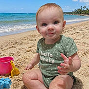 Arianna joined the competition — help win amazing prizes! baby, beach, sand, ocean, sky, bucket, shovel, toys, child, green_clothing, sitting, sunny, water, waves, smiling, cute, outdoor, holiday, play, nature