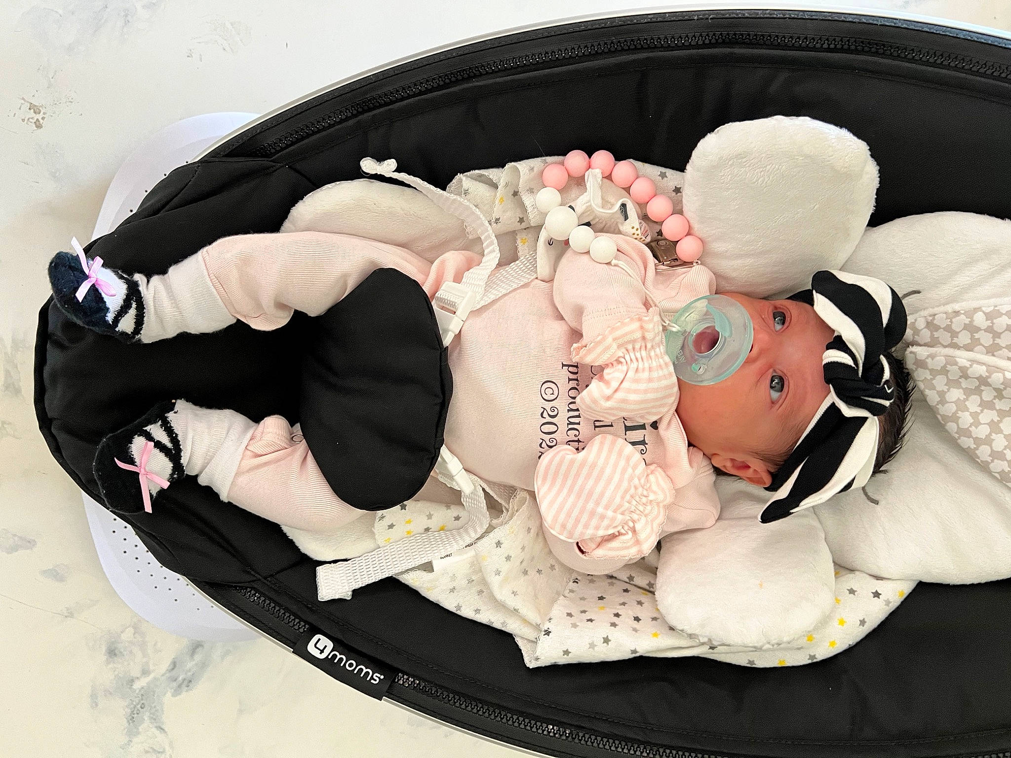 Amairani is registered to the contest to win money with this photo: baby, baby_products, baby_toddler_clothing, bag, child, comfort, costume_hat, embellishment, fashion_accessory, font, hair_accessory, headgear, headpiece, headwear, linens, pattern, person, pink, rose, sitting
