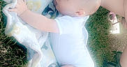 Erick is registered to the contest to win money with this photo: baby, blanket, clothing, diaper, dress, face, flower, footwear, grass, head, newborn, outdoors, person, petal, photography, plant, portrait, shoe, sleeping, toy