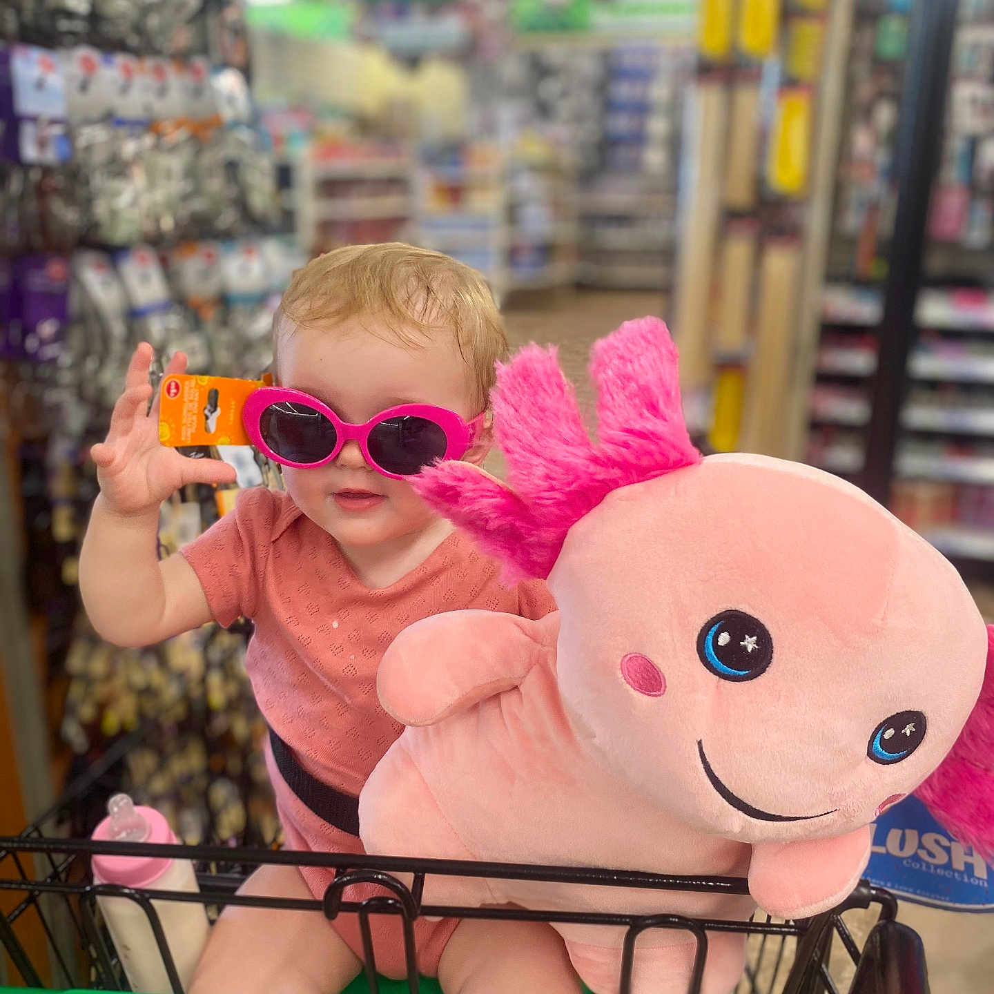 Violet joined the competition — help win amazing prizes! baby_bottle, child, child_in_cart, cute, dollar_tree, face, funny, holding, indoor, person, pink_clothing, pink_sunglasses, plush_toy, retail, shopping, shopping_cart, smiling, store_aisle, toddler, toy