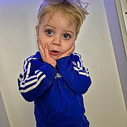 Greyson joined the competition — help win amazing prizes! child, blonde_hair, blue_eyes, scar, blue_sweatshirt, adidas, hands_on_face, expression, indoor, casual_clothing, portrait, young_child, curly_hair, standing, light_background, surprised, cute, sportswear, long_sleeves, face