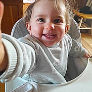 Pauline a rejoint le concours — aidez-le/la à gagner de superbes lots ! baby, child, toddler, smile, teeth, eyes, hair, messy_hair, highchair, bib, towel, hand, arm, indoor, wooden_floor, chair, furniture, portrait, closeup, happy