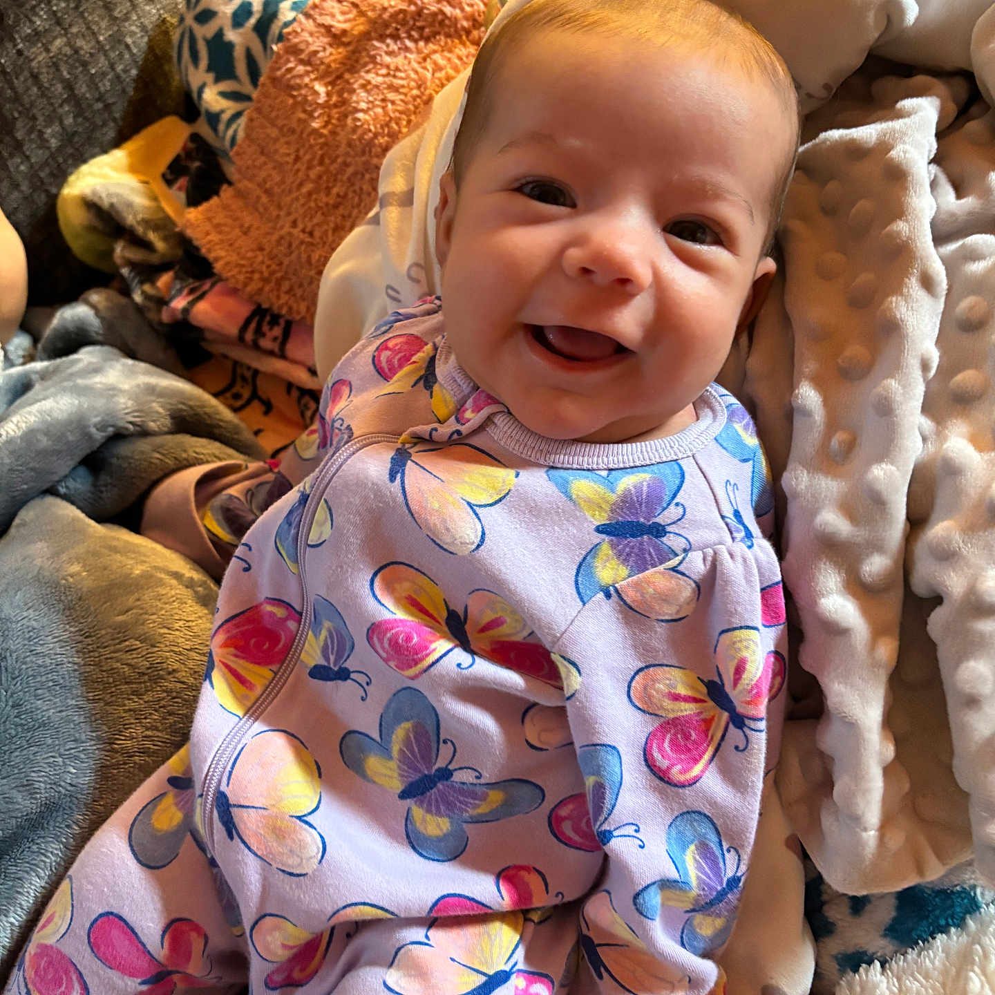 Adalyn joined the competition — help win amazing prizes! baby, blanket, butterfly_pattern, child, colorful_clothing, comfort, cozy, cushion, cute, face, happy, head, indoor, infant, newborn, onesie, person, portrait, smiling, soft_texture