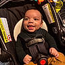baby, car_seat, child, smiling, infant, safety_belt, toy, orange_pants, black_shirt, happy, indoor, seat, child_safety, plaything, cute, portrait, secured, infant_toddler, baby_clothing, child_care