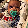Kayden is registered to the contest to win money with this photo: baby, pacifier, infant, clothing, face, hair, pattern, baby_seat, indoor, child, expression, toddler, text_on_clothing, cushion, comfort, closeup, person, cute, resting, seat