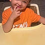 Adam is registered to the contest to win money with this photo: child, cute, expression, face, fingers, furniture, hair, hand, high_chair, indoor, orange_shirt, person, playful, portrait, seated, skin, smiling, table, toddler, young_child