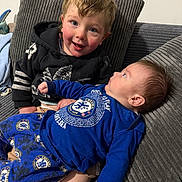 Teddie is registered to the contest to win money with this photo: toddler, baby, child, couch, pajamas, clothing, smile, face, hair, blue, black, cushion, indoor, sibling, cute, happy, person, portrait, cozy, family