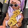 baby, car_seat, sunglasses, headband, bow, blanket, plush_giraffe, toy, infant, child, cute, sleeping, pink, purple, accessory, foot, hand, clothing, indoor, relaxing
