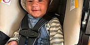 Zion is registered to the contest to win money with this photo: baby, car_seat, smiling, hat, striped_shirt, denim_overalls, indoor, wood_floor, seatbelt, child, infant, clothing, cute, sitting, person, baby_hand, headwear, casual, young_child, comfortable